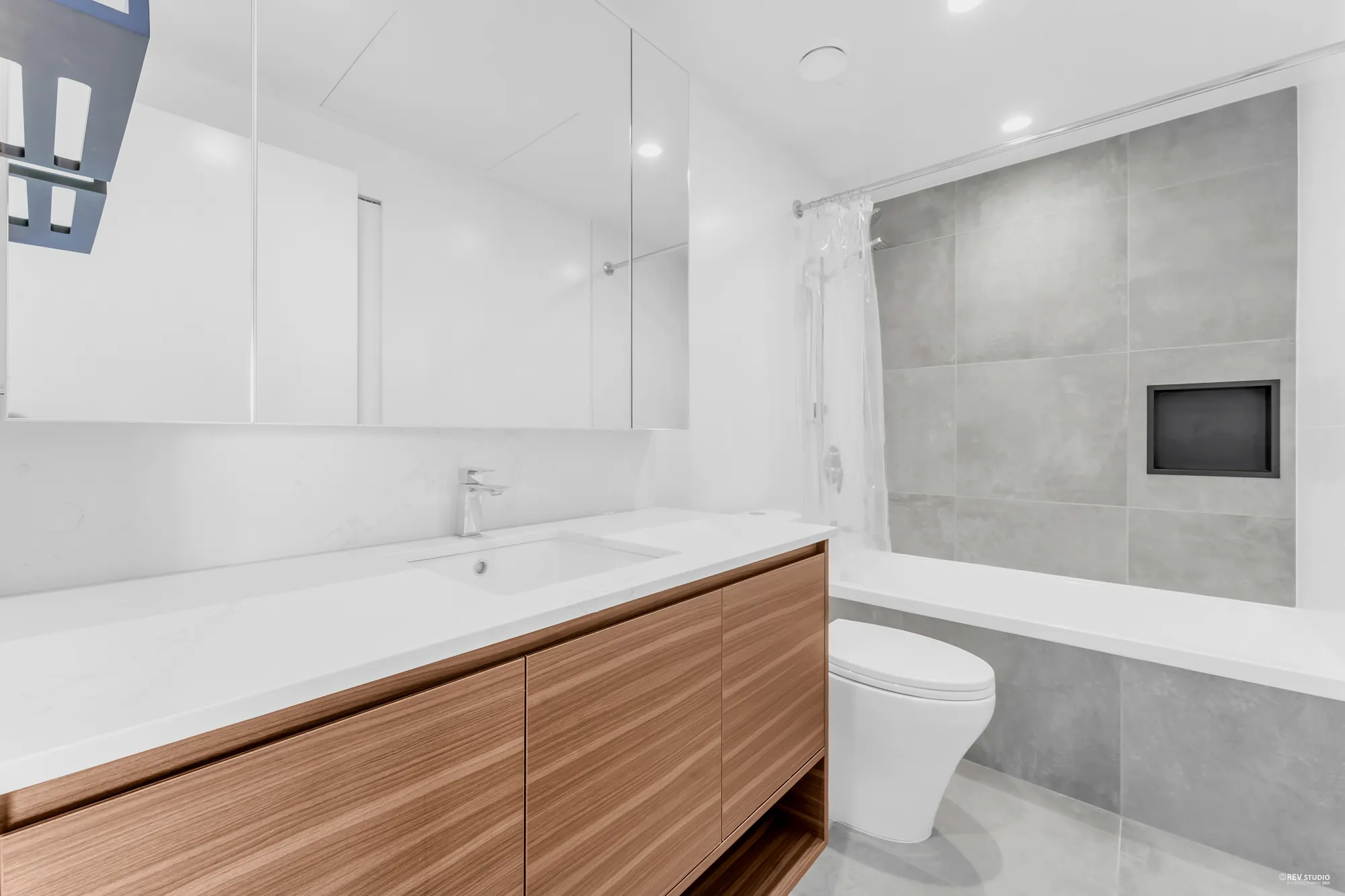 The 4-piece bathroom: tub-shower in grey tile, wood vanity