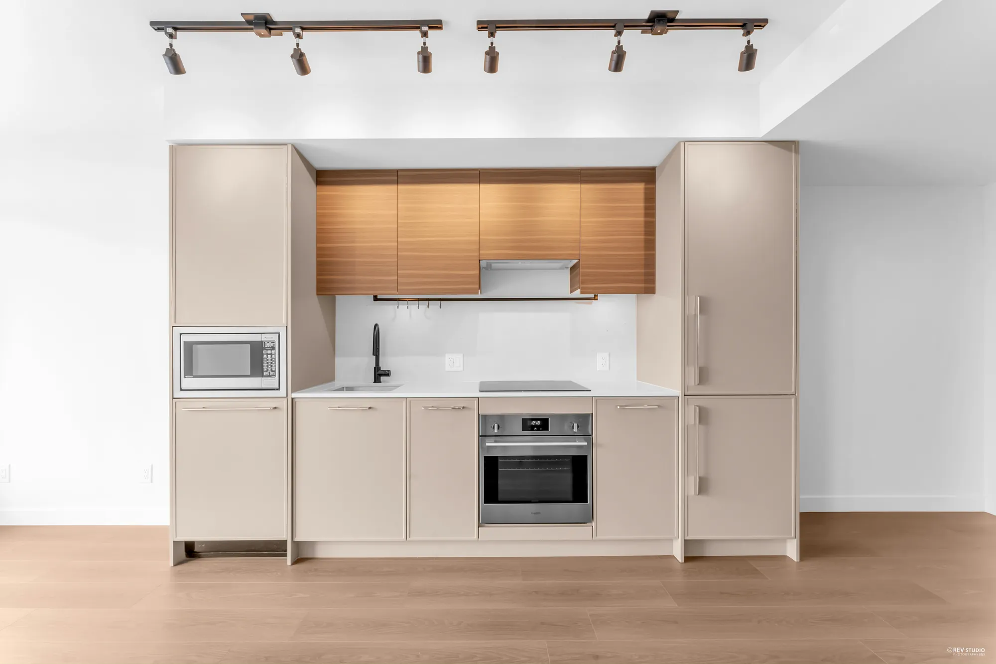 The kitchen run: oak uppers, pale lowers, wall oven and microwave, cooktop