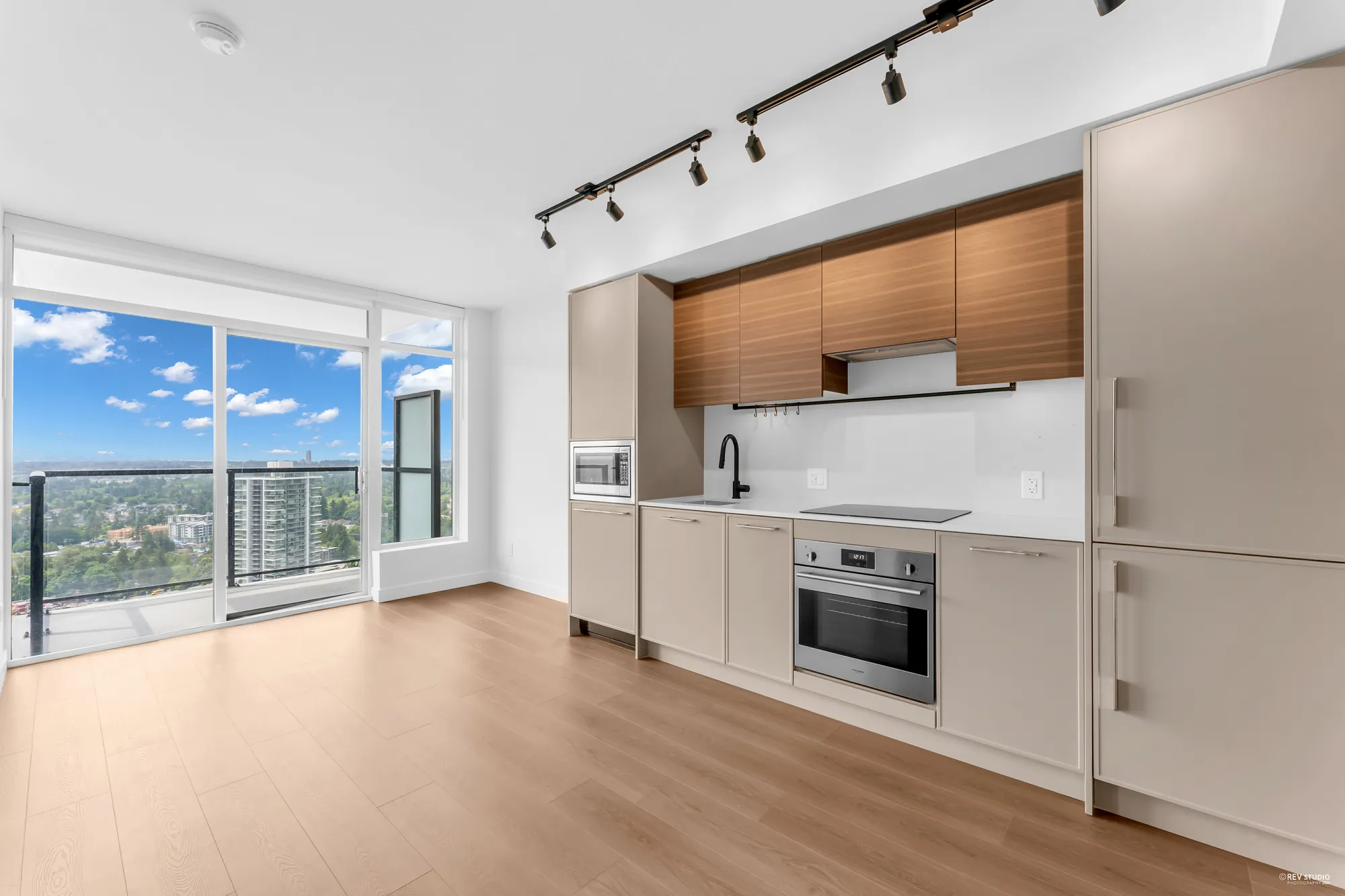 Living room and kitchen along the south wall of glass, balcony door at left
