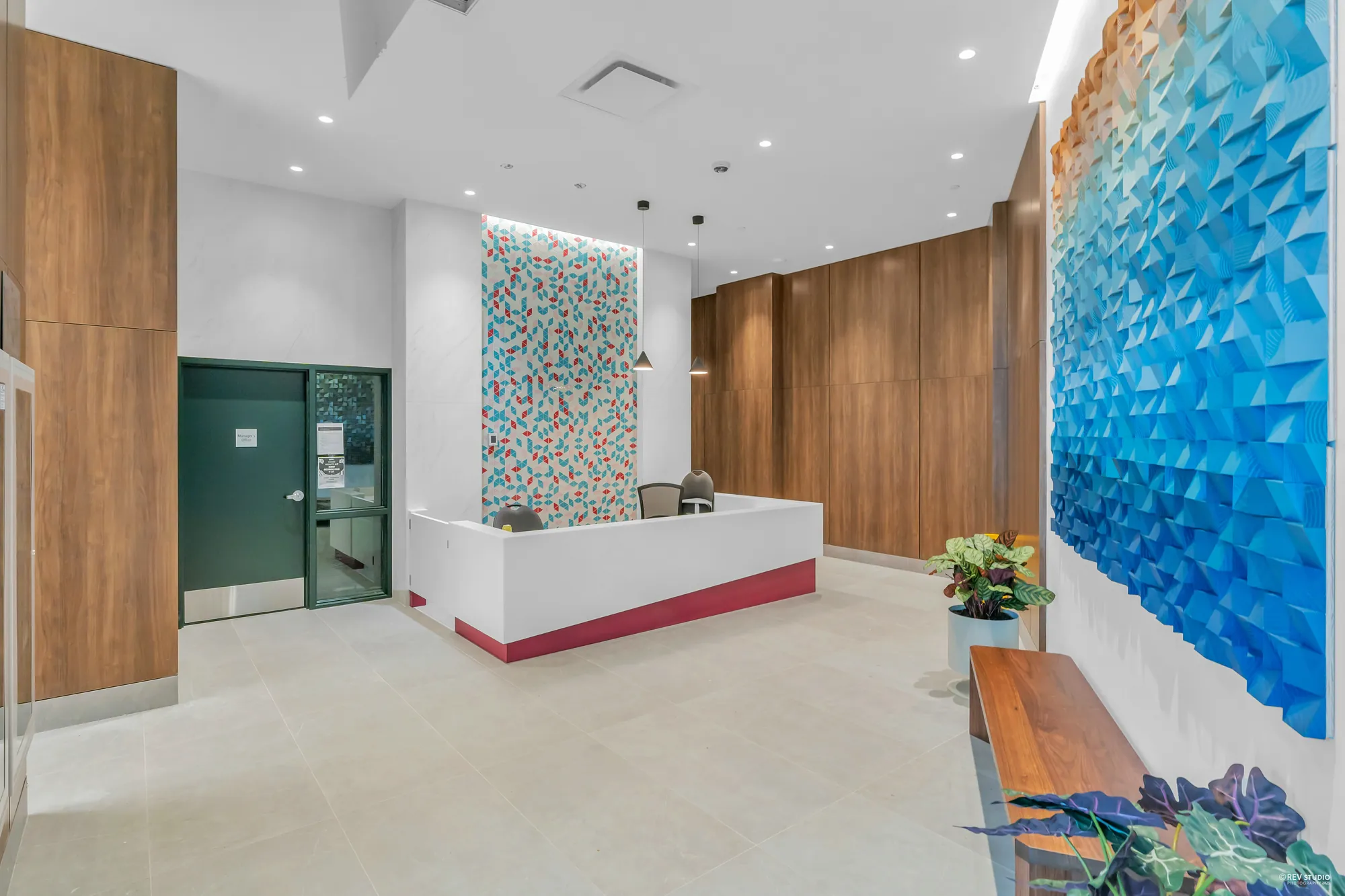The lobby: concierge desk, wood panelling and a faceted blue wall relief